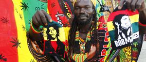 Ein Mitglied der Gruppe Ivoire Binghi bietet Kleidung und Fahnen während des "International Festivals of Abidjan Reggae" zum Verkauf an.