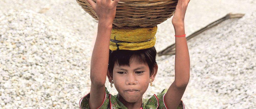 Eine Siebenjährige in Indien schleppt Steine aus einem Flussbett. 