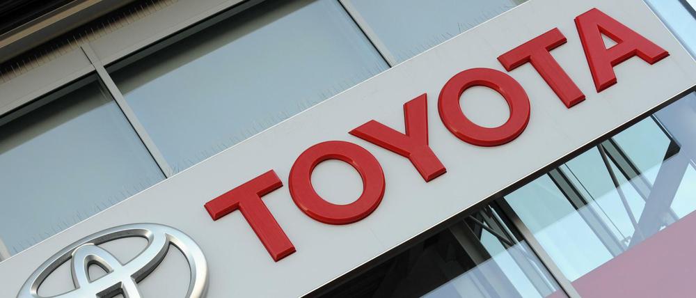 Das Logo des Automobilherstellers Toyota am Gebäude eines Händlers in München. 