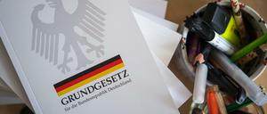 Eine Ausgabe des Grundgesetzes der Bundesrepublik Deutschland liegt auf einem Tisch neben Schreibutensilien.