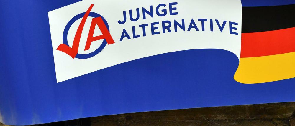 Ein Mann in schwarzen Sandalen hält ein Plakat der AfD-Jugendorganisation Junge Alternative (JA).