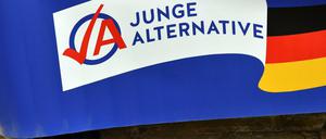 Ein Mann in schwarzen Sandalen hält ein Plakat der AfD-Jugendorganisation Junge Alternative (JA). 