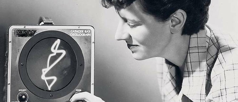 Die Filmemacherin Mary Ellen Bute mit einem Oszilloskop, das elektrische Spannung in einem Koordinatensystem darstellt.