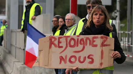 Eine Demonstrantin hält ein Schild mit der Aufschrift "Schließt euch uns an" in ihren Händen.