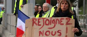 Eine Demonstrantin hält ein Schild mit der Aufschrift "Schließt euch uns an" in ihren Händen.