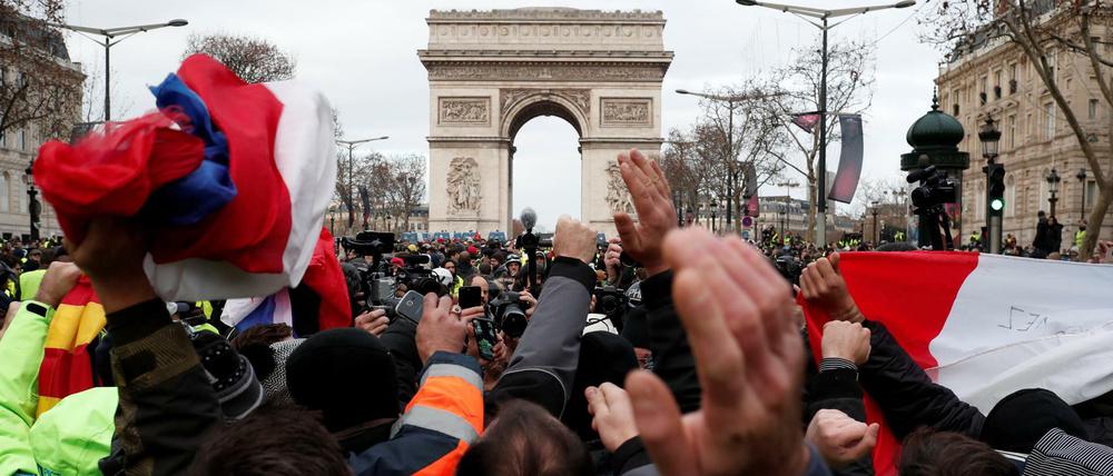 Demonstranten schwenken französische Flaggen vor dem Arc de Triomphe in Paris.