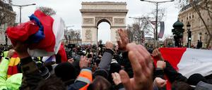 Demonstranten schwenken französische Flaggen vor dem Arc de Triomphe in Paris.