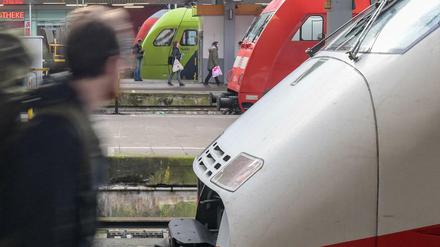 Ein Reisender läuft am Bahnhof an wartenden Zügen entlang.