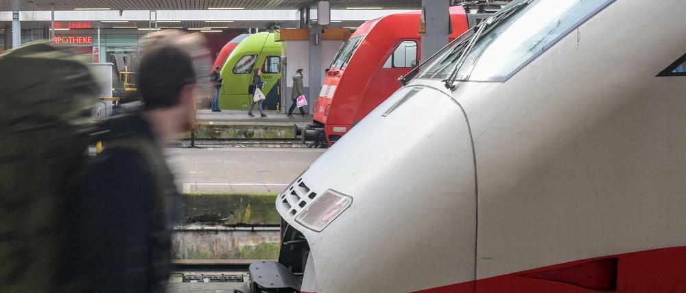 Ein Reisender läuft am Bahnhof an wartenden Zügen entlang.