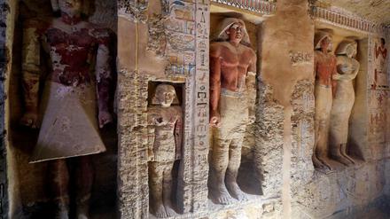 Blick in die jetzt geöffnete Grabkammer mit Statuen und farbigen Wandreliefs.