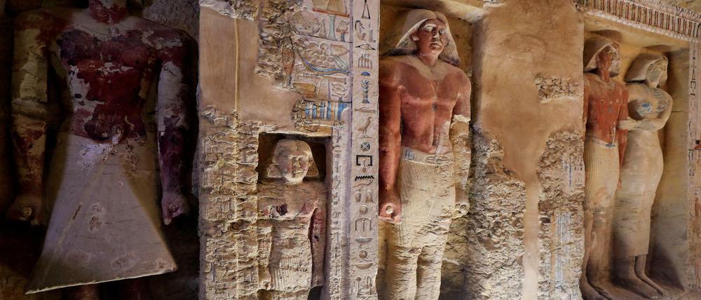 Blick in die jetzt geöffnete Grabkammer mit Statuen und farbigen Wandreliefs.
