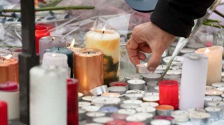 Eine Frau legt auf einem Sockel nahe des Weihnachtsmarktes in Straßburg eine Kerze hin.
