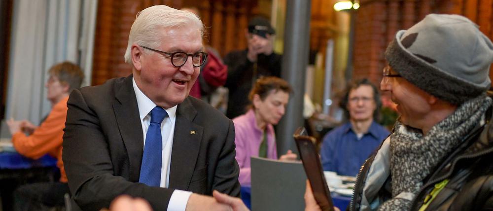 Bundespräsident Frank-Walter Steinmeier (l, SPD) unterhält sich mit Bedürftigen bei Tisch.