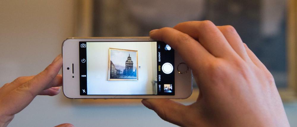 Eine Frau fotografiert in der Gemäldegalerie Alte Meister in Dresden das Ölgemälde "Die ehemalige Kreuzkirche in Dresden" von Bernardo Bellotto.