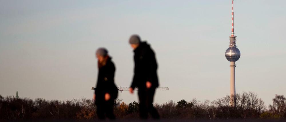 Spaziergänger gehen auf dem Tempelhofer Feld vor dem Berliner Fernsehturm. Statt Schnee ist es in Deutschland grau und trüb. 