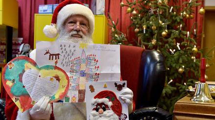 Der Weihnachtsmann zeigt die Wunschzettel von Mia Sophie aus Berlin, Jeremy aus Welzow und Laila aus Berlin.