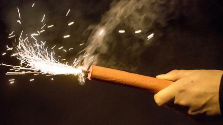 Angezündeter Feuerwerkskörper in einer Hand.