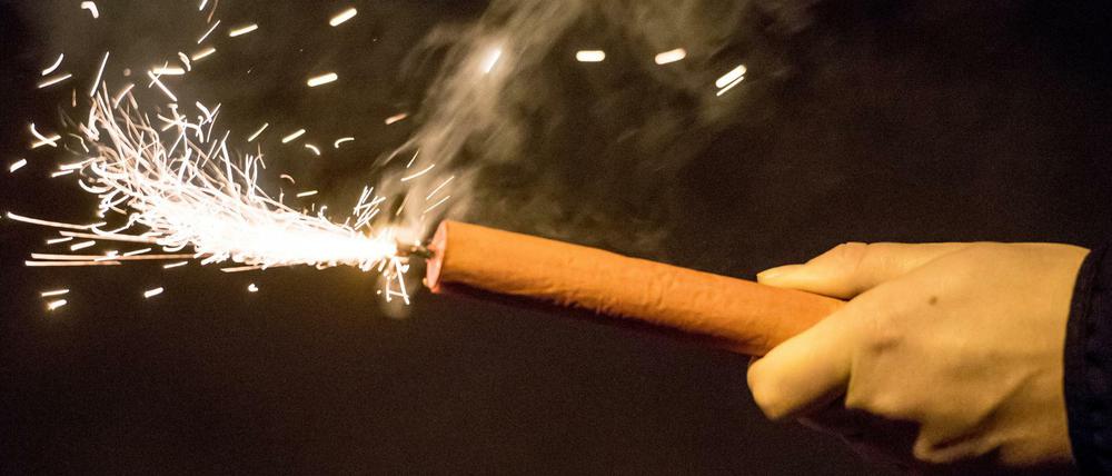 Angezündeter Feuerwerkskörper in einer Hand.