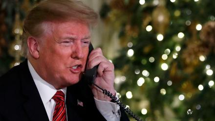 Donald Trump, Präsident der USA, sitzt am Telefon und gibt Updates über das Bewegungsprofil des Weihnachtsmannes.