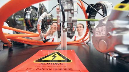 Neue Technik. Auszubildende beim Autobauer Porsche an einem Modell eines Hybridsystems.