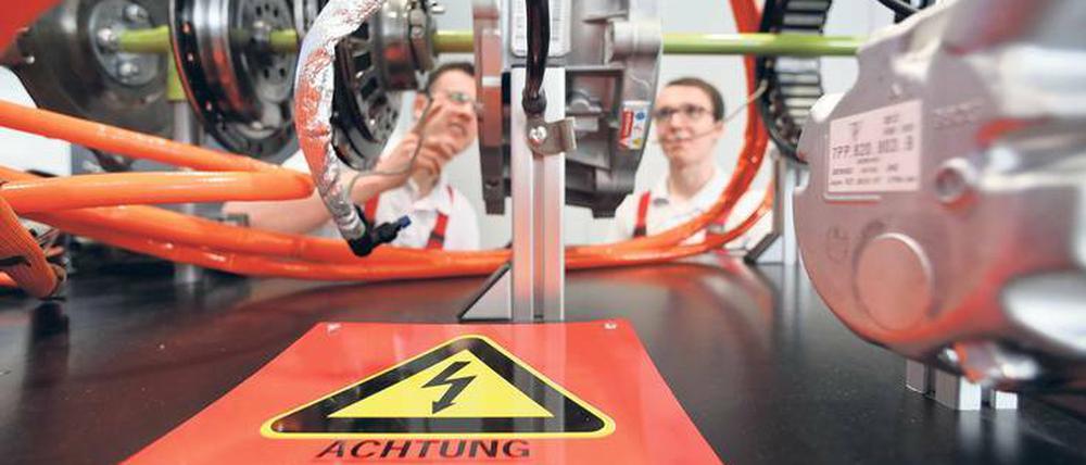 Neue Technik. Auszubildende beim Autobauer Porsche an einem Modell eines Hybridsystems.