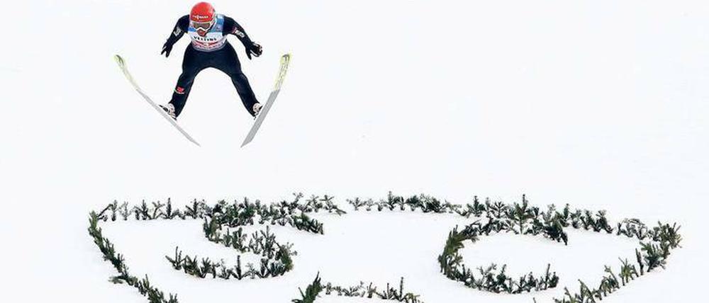 Hoch und weit. Markus Eisenbichler fliegt an der Großen Olympiaschanze über das Logo des SC Partenkirchen.