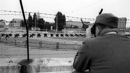 Gefährlicher Grenzstreifen. Ein Wachposten beobachtet den Grenzstreifen der Berliner Mauer am Potsdamer Platz, Personen (1961).