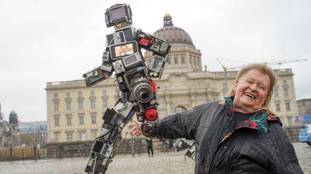 17.11.2021, Berlin: Der Künstler und Umweltaktivist HA Schult steht vor seinem Kunstwerk «Der Wertgigant» auf dem Schinkelplatz. Die Skulptur ist sechs Meter hoch, drei Tonnen schwer und besteht ausschließlich aus weggeworfenem Elektroschrott - den deutsche Haushalte in 72 Sekunden produzieren. Foto: Jörg Carstensen/dpa - 