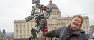 17.11.2021, Berlin: Der Künstler und Umweltaktivist HA Schult steht vor seinem Kunstwerk «Der Wertgigant» auf dem Schinkelplatz. Die Skulptur ist sechs Meter hoch, drei Tonnen schwer und besteht ausschließlich aus weggeworfenem Elektroschrott - den deutsche Haushalte in 72 Sekunden produzieren. Foto: Jörg Carstensen/dpa - 