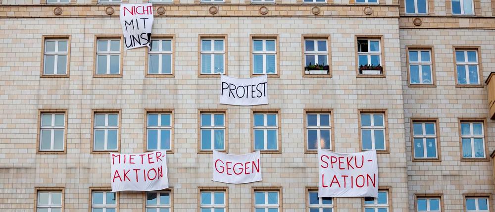 Berlin: Plakate gegen den Verkauf von Mietwohnungen an die Deutsche Wohnen SE hängen an einer Gebäudefassade in der Karl-Marx-Allee.