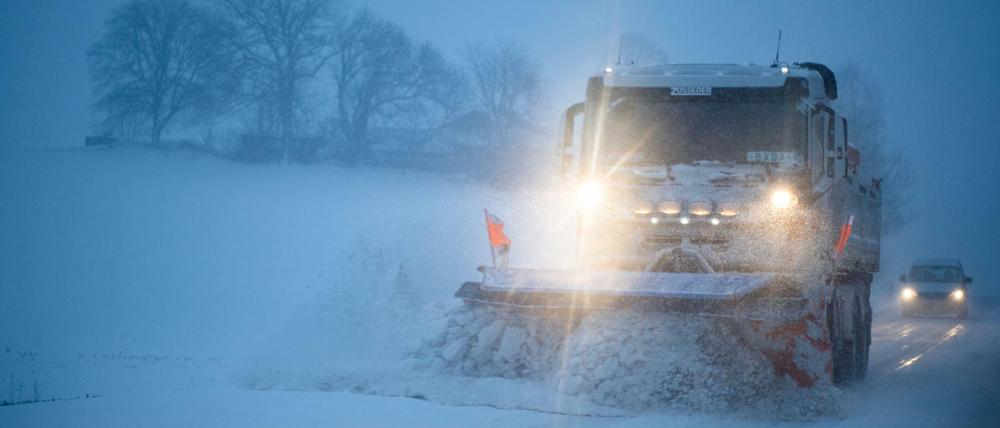 Ein Schneepflug räumt Schnee auf einer Landstraße. In Bayern haben in der Nacht starke Schneefälle eingesetzt.