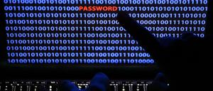 Ein Finger zeigt auf das Wort "Password", das zwischen Zeichen des Binärcode auf einem Computerbildschirm steht.