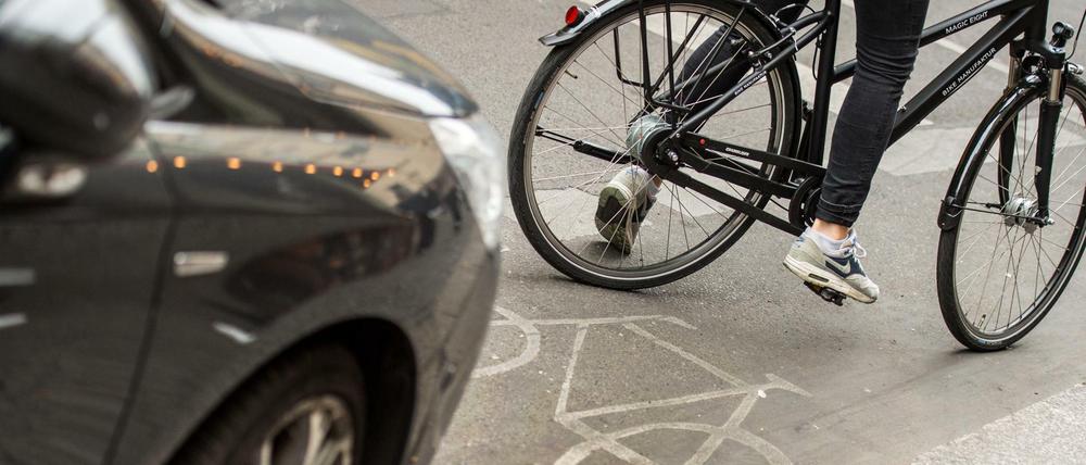 Eine Radfahrerin umfährt in Berlin ein auf dem Radweg stehendes Auto