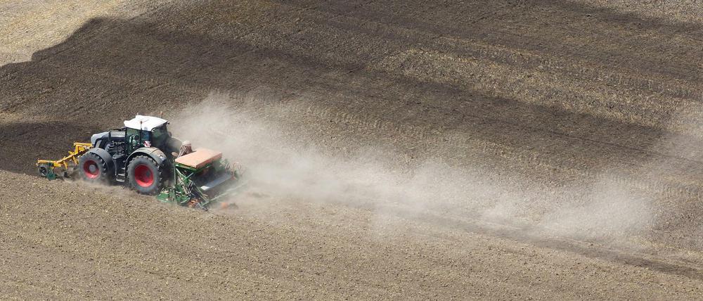 Ein Landwirt bearbeitet mit seinem Traktor ein ausgetrocknetes Feld.