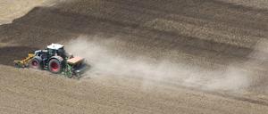 Ein Landwirt bearbeitet mit seinem Traktor ein ausgetrocknetes Feld.
