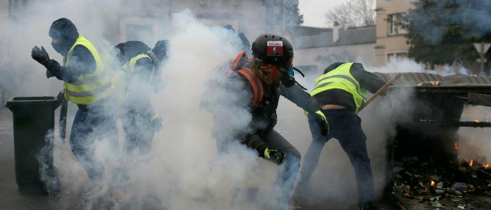 Teilnehmer einer Demonstration der "Gelbwesten" in Bourges gehen in Deckung, als die Polizei Tränengas einsetzt.