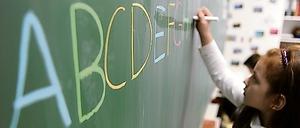 Eine Schülerin schreibt in einer Schule in Hamburg das ABC an die Tafel. 