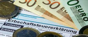 Formulare für die Erbschaftssteuererklärung des Finanzamtes zwischen Euro-Banknoten und Münzen