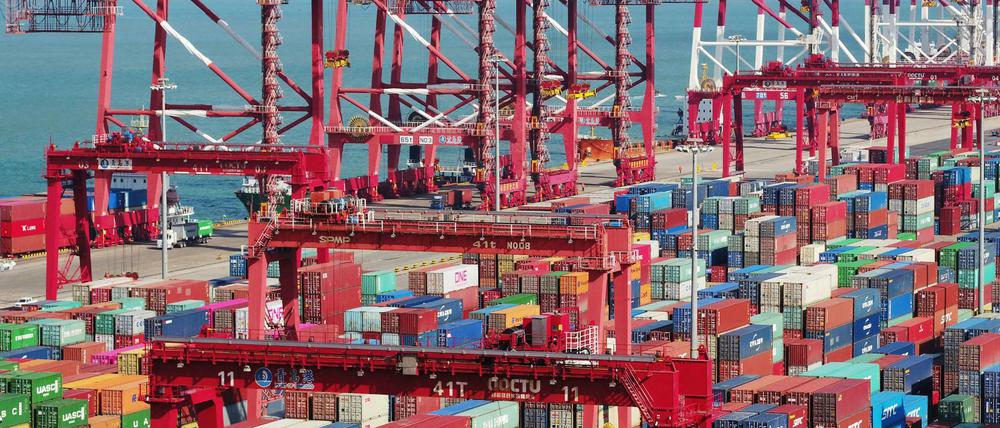 In einem Hafen im chinesischen Qingdao stehen Container und Containerbrücken.