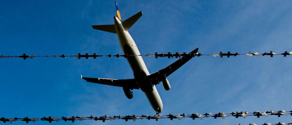 Ein Flugzeug fliegt über Stacheldraht hinweg. (Symbolbild)