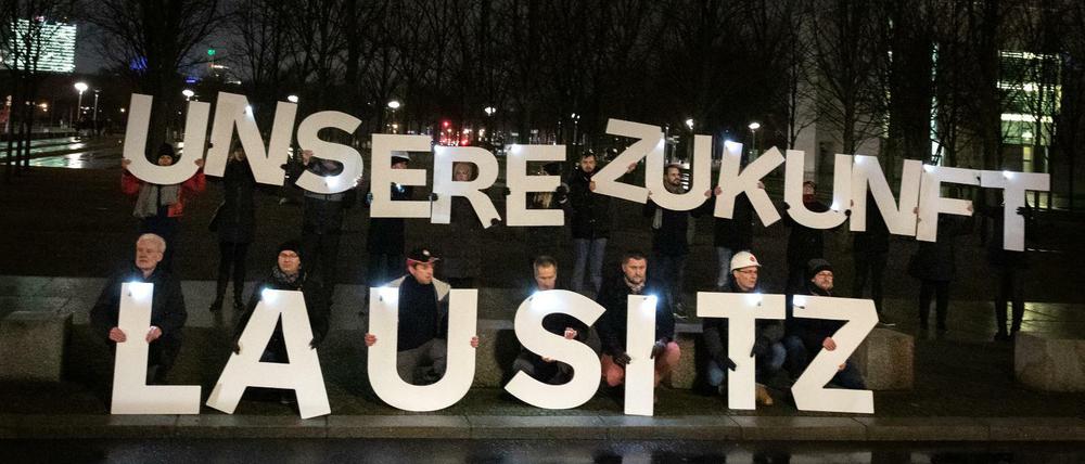 20 Menschen protestieren vor dem Kanzleramt in Berlin für Kohleverstromung. 