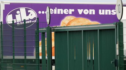 Lkw des Bäckereiunternehmens "Lila Bäcker" stehen am Produktionsstandort der Bäckerei hinter einem Zaun.