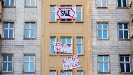 Plakate gegen den Verkauf von Mietwohnungen an die Deutsche Wohnen hängen an einer Gebäudefassade in der Karl-Marx-Allee.
