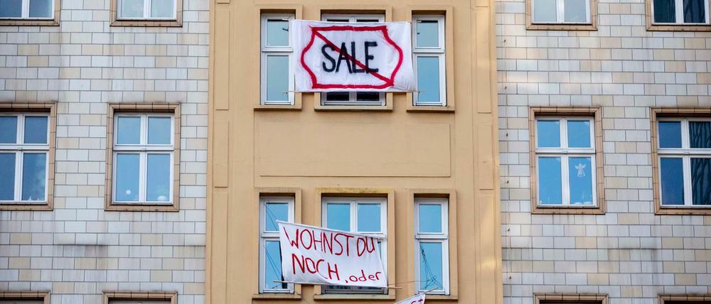 Plakate gegen den Verkauf von Mietwohnungen an die Deutsche Wohnen hängen an einer Gebäudefassade in der Karl-Marx-Allee.