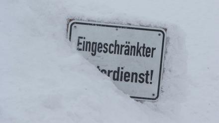 Bei eisiger Kälte auf dem Brocken steckt ein Schild mit der Aufschrift "Eingeschränkter Winterdienst" im Schnee. 