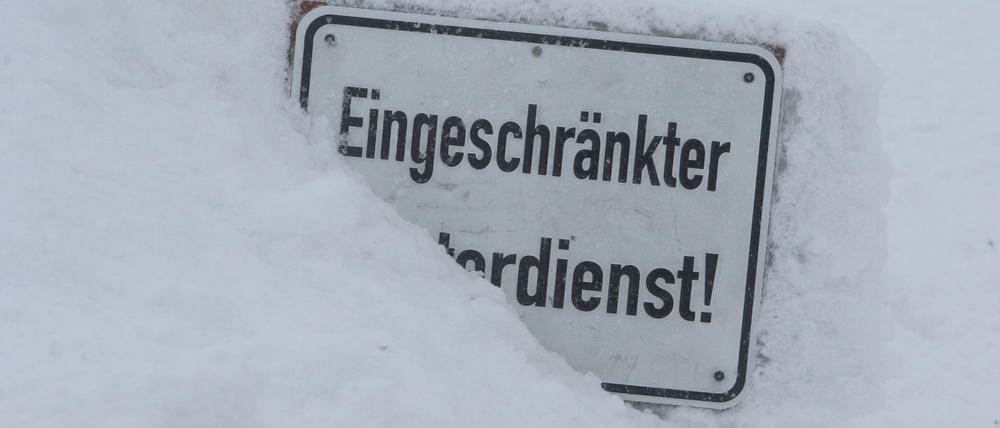 Bei eisiger Kälte auf dem Brocken steckt ein Schild mit der Aufschrift "Eingeschränkter Winterdienst" im Schnee.
