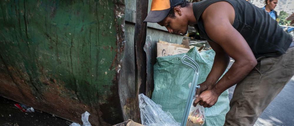 Ein Mann in Caracas durchsucht den Müll nach Essensresten.