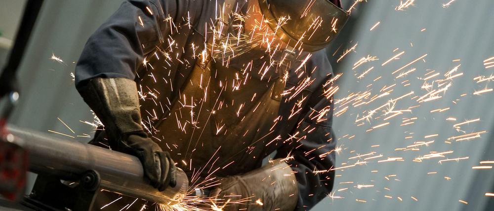 Ein Arbeiter benutzt in einer Fabrik der Hess Lichttechnik GmbH eine Schleifmaschine. 
