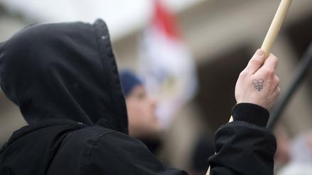 Ein Demonstrant mit dem Tattoo einer Rune und einer Fahne auf einer NPD-Demonstration.