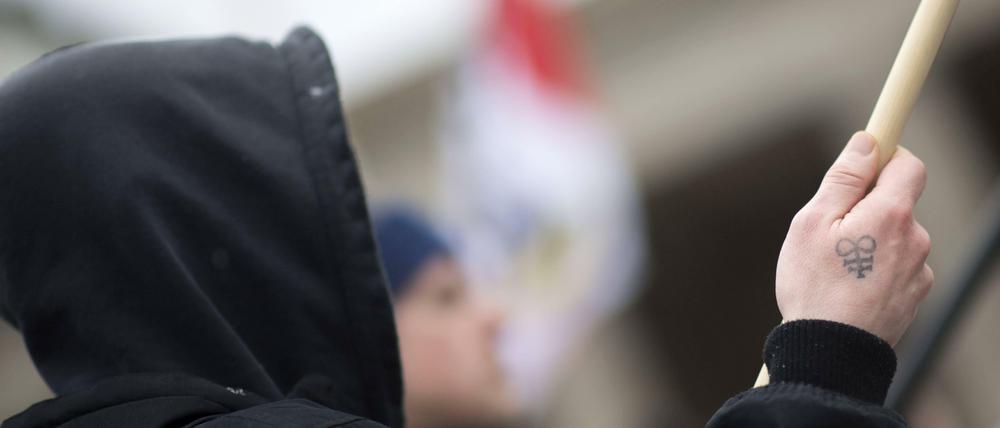 Ein Demonstrant mit dem Tattoo einer Rune und einer Fahne auf einer NPD-Demonstration.